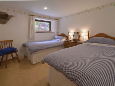 A bedroom with two single beds wooden chair and a wooden dresser with lamps at Water Barn in Manaton near Lustleigh