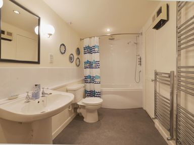 A bathroom with a sink a toilet a bathtub with shower and shower curtain and a heated towel rail at Water Barn in Manaton near Lustleigh