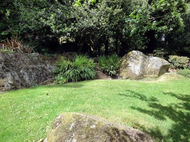 A garden with grass boulders and trees at Water Barn in Manaton near Lustleigh