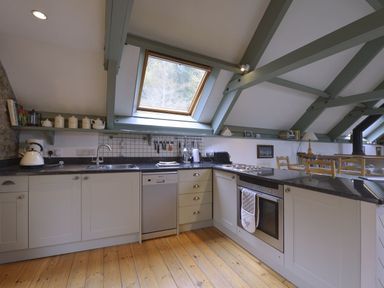 A kitchen with white cabinets wooden floor and a skylight window at Water Barn in Manaton near Lustleigh