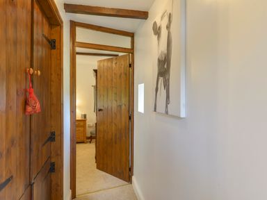 A hallway with wooden doors and a black and white painting of a cow at Buster Barn in Sampford Spiney near Tavistock
