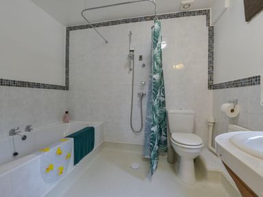 A bathroom with a bathtub towel and shampoo a shower area with a curtain a toilet and a sink at Buster Barn in Sampford Spiney near Tavistock
