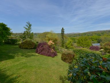 A garden with various shrubs trees and a green lawn at Buster Barn in Sampford Spiney near Tavistock