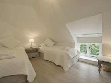 A bedroom with two single beds a nightstand with a lamp and a window with a white blind at Cullaford Cottage in Scorriton near Ashburton