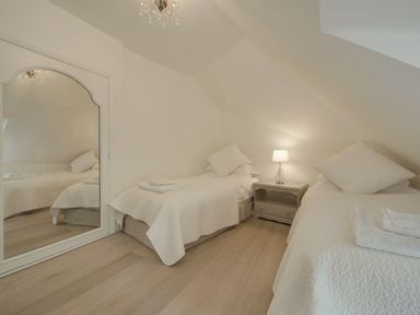 A bedroom with two single beds a bedside table with a lamp and a large wall mirror at Cullaford Cottage Scorriton near Ashburton