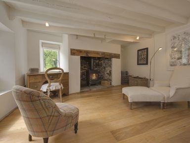 A living room with a fireplace desk wooden chair and upholstered chairs at Cullaford Cottage in Scorriton near Ashburton