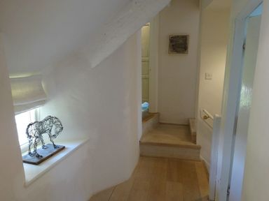 A hallway with wooden floors and steps a small window with a wire horse sculpture and a framed picture on the wall at Cullaford Cottage in Scorriton near Ashburton