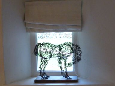 A wire sculpture of an elephant on a windowsill with a fabric blind above at Cullaford Cottage in Scorriton near Ashburton