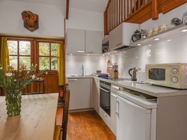 A kitchen with white cabinets a microwave kettle and flowers on a table at Townend Barn in Lydford
