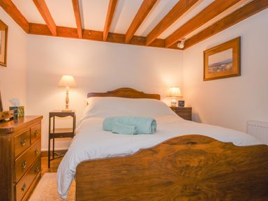 A bedroom with a wooden bed and dresser with two lamps on bedside tables at Townend Barn in Lydford