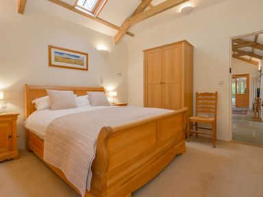 A bedroom with a wooden bed a wardrobe a chair and bedside tables with lamps at Burham Barn in Dousland near Yelverton