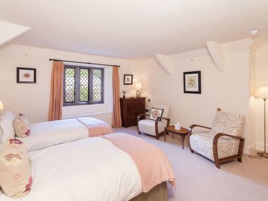 A bedroom with two beds two armchairs a chest of drawers and a window at Great Bidlake Manor Bridestowe near Lydford