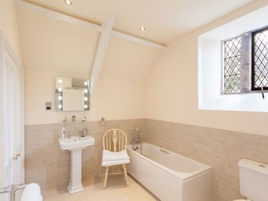 A bathroom with a bathtub sink toilet wooden chair and a window at Great Bidlake Manor in Bridestowe near Lydford