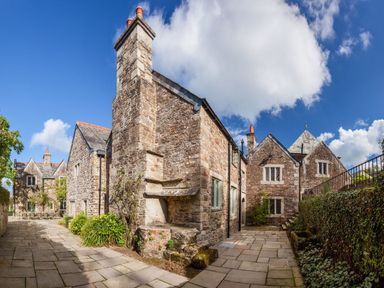 An outdoor courtyard with stone buildings and a large chimney at Great Bidlake Manor in Bridestowe near Lydford