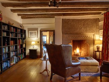 A living room with a fireplace and bookshelf at Great Bidlake Manor in Bridestowe, near Lydford