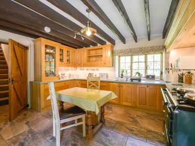 A kitchen with wooden cabinets a table and chairs near a window at Bagtor Mill in Ilsington near Haytor Vale