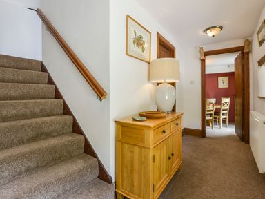 A hallway with carpeted stairs wooden sideboard with a lamp and an open doorway to a dining room at Bagtor Mill in Ilsington near Haytor Vale