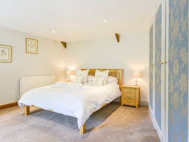 A bedroom with a wooden bed and nightstands with lamps at Bagtor Mill in Ilsington near Haytor Vale