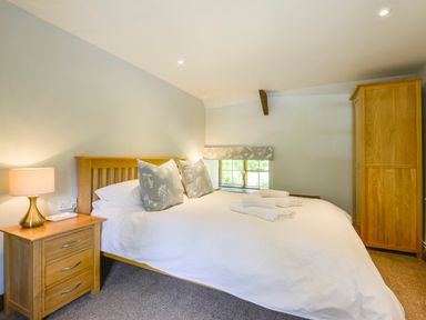 A bedroom with a bed bedside table lamp and wooden wardrobe at Bagtor Mill in Ilsington near Haytor Vale