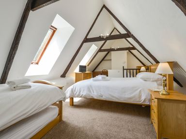 A bedroom with two beds wooden furniture and exposed ceiling beams at Bagtor Mill in Ilsington near Haytor Vale