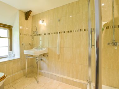 A bathroom with a sink next to a window and a glass shower enclosure at Bagtor Mill in Ilsington near Haytor Vale