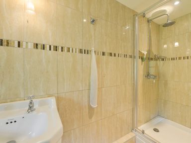 A bathroom with a sink and a walk-in shower with glass door at Bagtor Mill in Ilsington near Haytor Vale