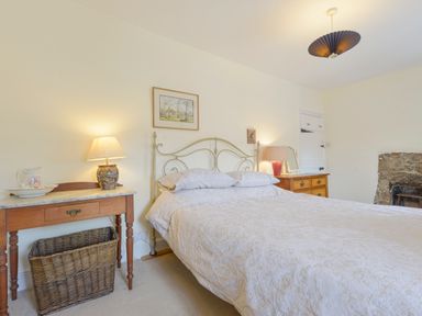 A bedroom with a bed two bedside tables lamps and a wicker basket at Little Gate Cottage in North Bovey