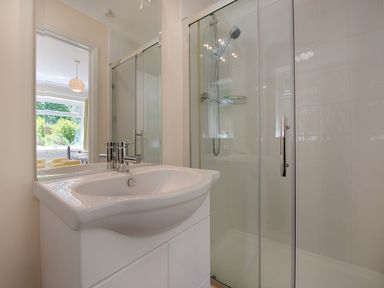 A bathroom with a white sink and a glass shower enclosure with a showerhead at Exe View in Dawlish