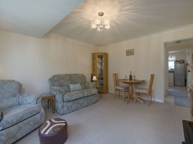 A living room with two sofas a small round dining table with two chairs and a glass cabinet at Exe View in Dawlish