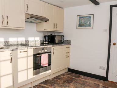 A kitchen with cream cabinets stainless steel oven kettle and microwave on granite countertop in Sandridge Barton Stoke Gabriel