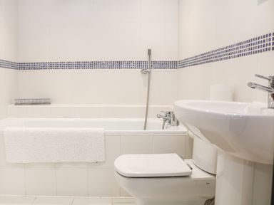A bathroom with a bathtub shower toilet sink and a towel on the bathtub at Sandridge Barton in Stoke Gabriel