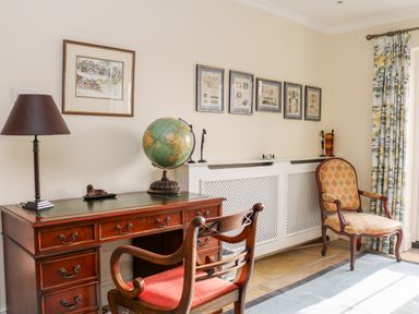 A room with a wooden desk and chair a globe lamp and framed pictures on the wall at Sandridge Barton in Stoke Gabriel