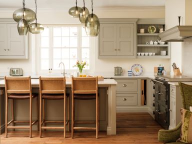 A kitchen with bar stools and cabinets at Sandridge Barton Stoke Gabriel