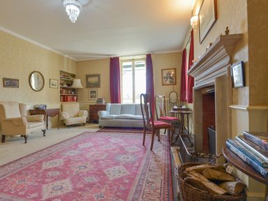 A living room with armchairs a sofa fireplace and a red carpet at Wootton House in Butleigh Wootton near Compton Dundon