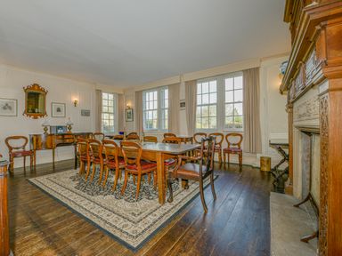 A dining room with wooden chairs a large table and a fireplace at Wootton House in Butleigh Wootton near Compton Dundon
