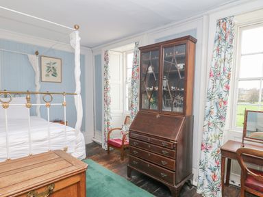 A bedroom with a four poster bed a wooden chest a glass-front cabinet and floral curtains at Wootton House in Butleigh Wootton near Compton Dundon