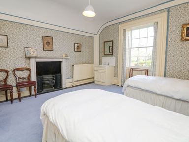 A bedroom with two single beds a fireplace two chairs and a window at Wootton House in Butleigh Wootton near Compton Dundon