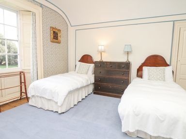 A bedroom with two single beds a wooden chest of drawers and a window at Wootton House in Butleigh Wootton near Compton Dundon