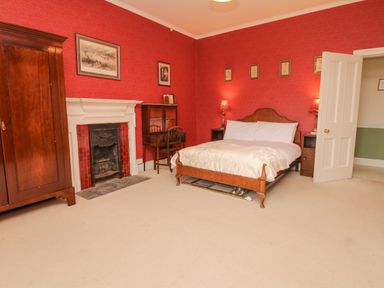A bedroom with a wooden bed and desk and an open door at Wootton House in Butleigh Wootton near Compton Dundon