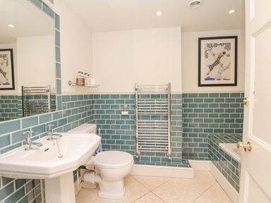 A bathroom with a pedestal sink toilet blue tiled walls a heated towel rail and a bathtub at Wootton House in Butleigh Wootton near Compton Dundon