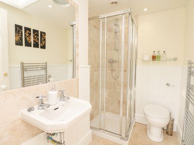 A bathroom with a sink, shower enclosure, toilet, towel radiator, and wall art at Wootton House in Butleigh Wootton near Compton Dundon