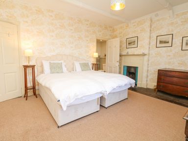 A bedroom with a double bed bedside tables lamps a fireplace and a wooden dresser at Wootton House in Butleigh Wootton near Compton Dundon