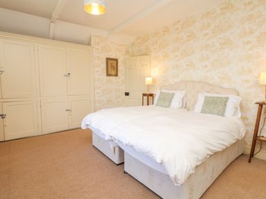 A bedroom with a double bed two bedside lamps a large wardrobe and patterned wallpaper at Wootton House in Butleigh Wootton near Compton Dundon