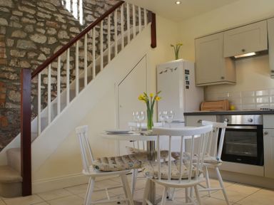 A kitchen with a staircase and a table at The Barn in Compton Bishop, near Cheddar