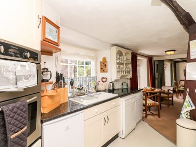 A kitchen with a black countertop oven and utensils next to a window and a dining area at Castle View in Dunster