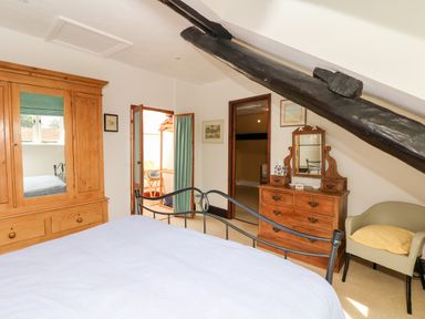 A bedroom with a bed an armoire a dresser with a mirror and a chair at Castle View in Dunster