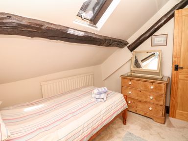 A bedroom with a bed and wooden dresser under a skylight at Castle View in Dunster