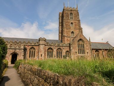 A stone church with a tower and arched windows with a path and grassy area in front of it