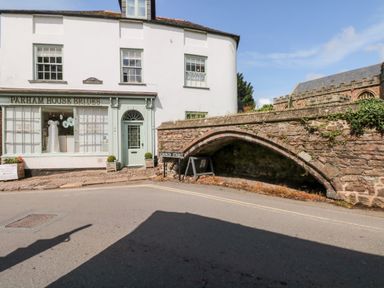 A bridal shop next to a stone arch bridge on a street with a church building in the background