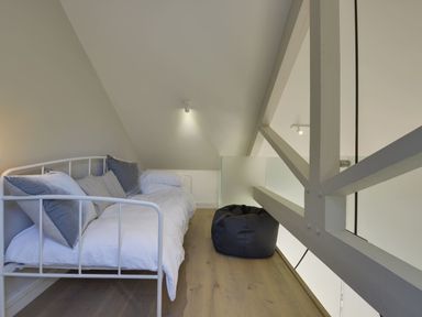 A small bedroom with a single bed and pillows and a bean bag chair at Grooms Cottage in Talaton near Ottery St Mary